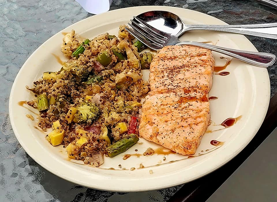 Grilled salmon with quinoa salad on a beige plate.