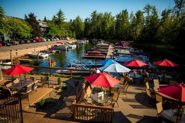 Outdoor dining area with colorful umbrellas by a waterfront marina.