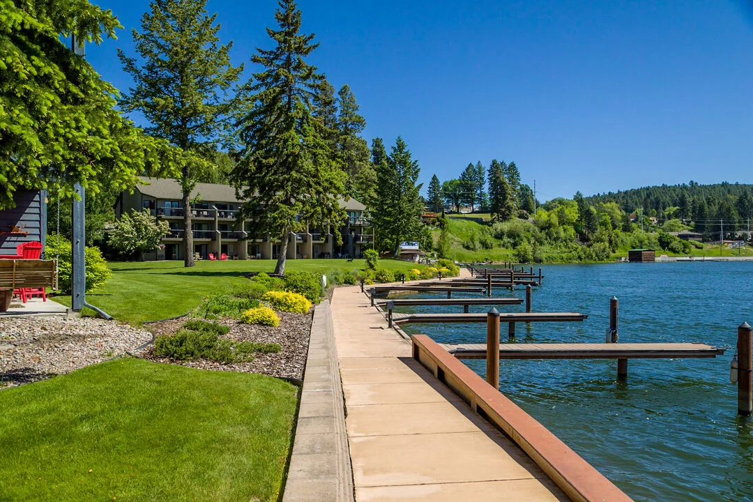 Lakeside walkway with docks and greenery.